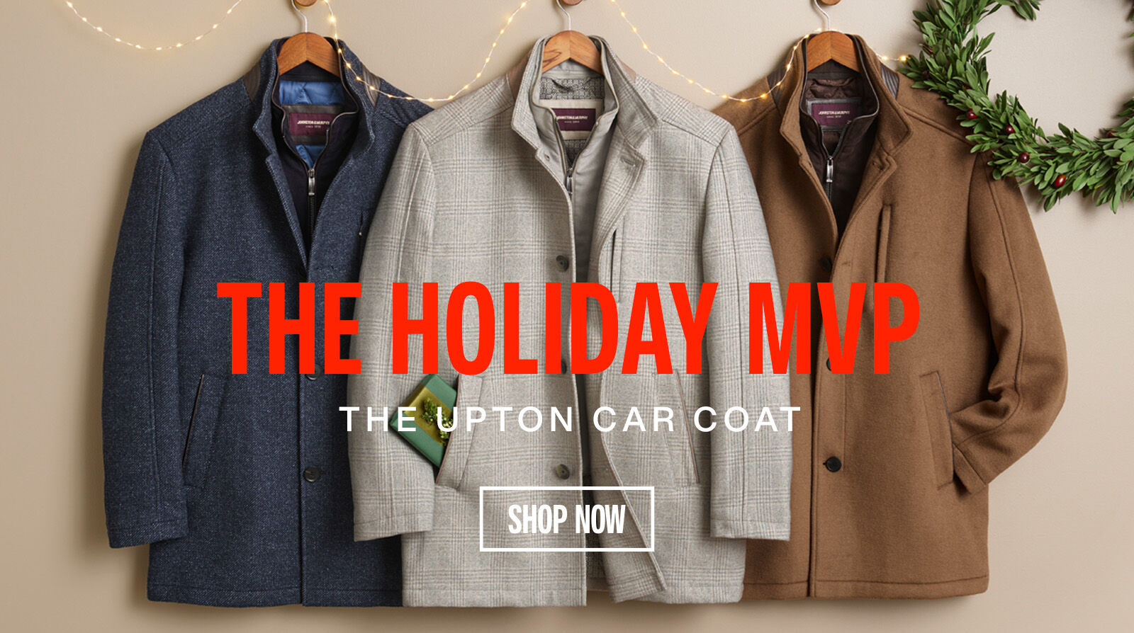 Three men's Upton Car Coats hung on a wall with surrounding holiday decoration. 